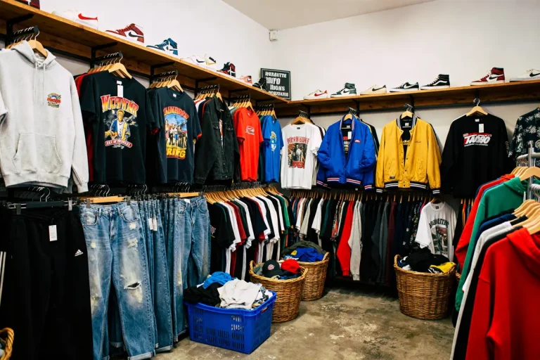 Vêtements vintage colorés et chaussures exposés chez Yemma friperie sur des cintres et étagères