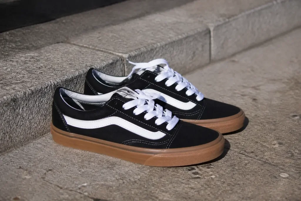 Chaussures noires avec semelles marron sur marches, modèle Vans Slip-On.